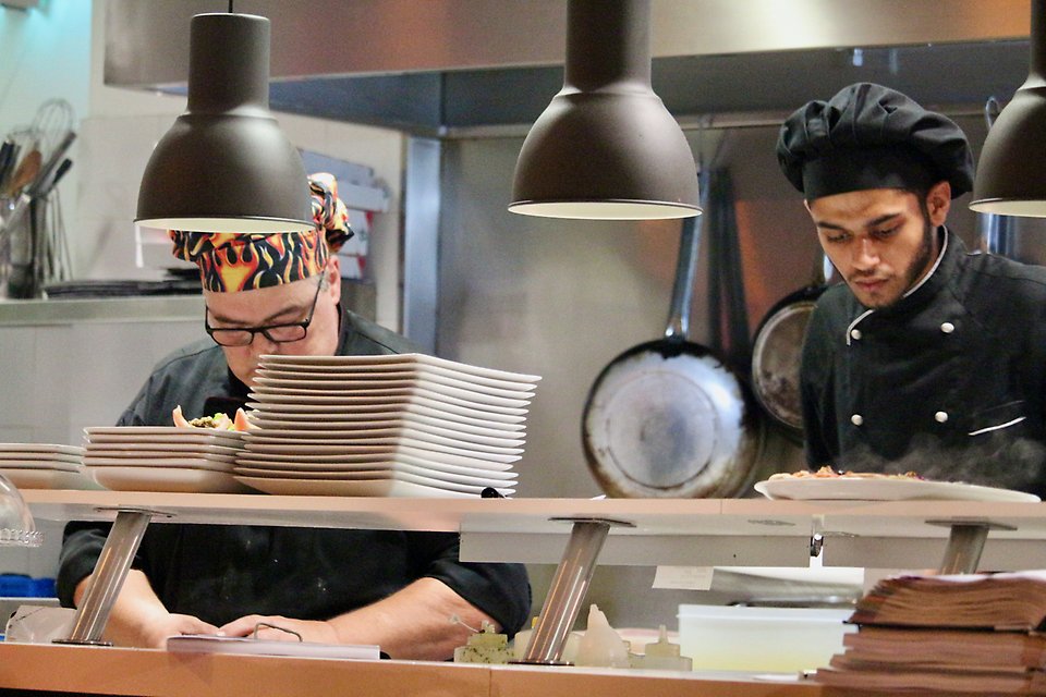 Två koncentrerade kockar arbetar i restaurangkök.